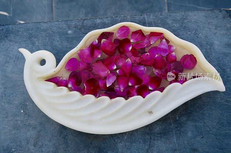 红玫瑰花瓣漂浮在水盘上，传统的印度家庭/酒店/寺庙欢迎客人的照片